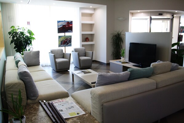 A modern living room with a sofa, armchairs, a coffee table, and a flat-screen TV.