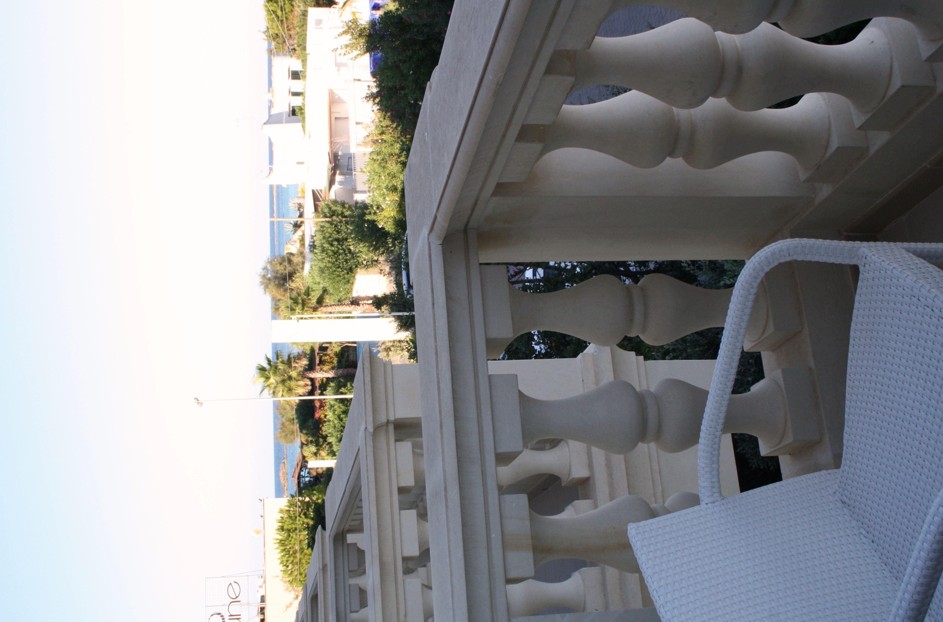Ein Balkon mit einem weißen Stuhl und Blick auf Gebäude und Bäume.