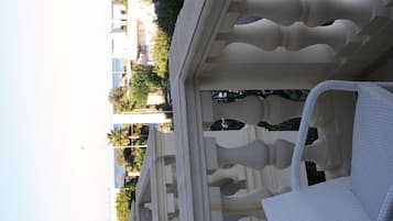 Ein Balkon mit einem weißen Stuhl und Blick auf Gebäude und Bäume.
