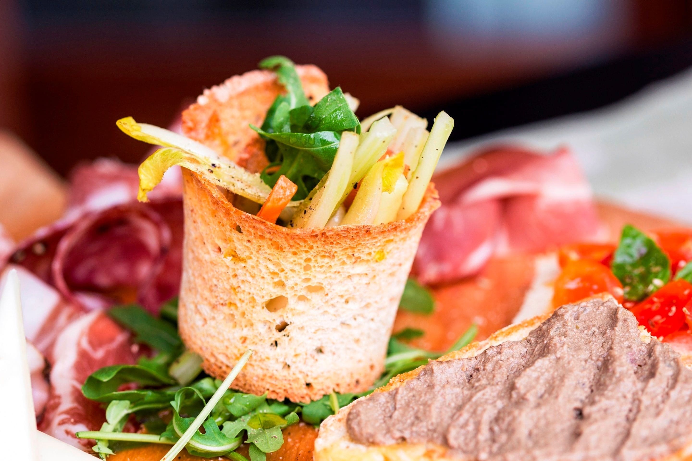 Gros plan d’un plateau de nourriture contenant divers éléments, notamment un panier de pain, de la viande et des légumes.