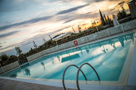 Una piscina al aire libre, sombrillas, tumbonas