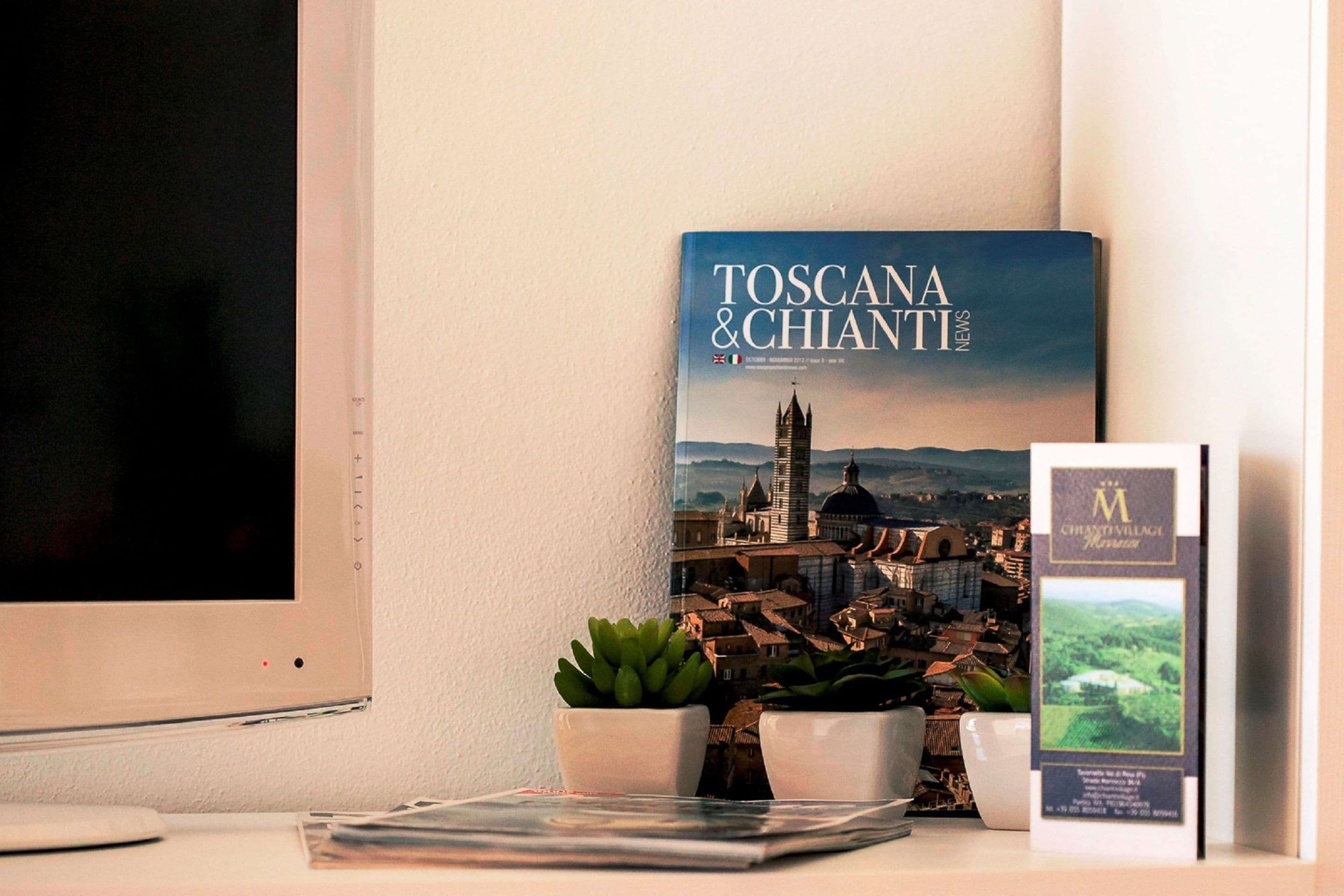 Un livre intitulé « Toscane et Chianti » est posé sur une table, à côté d’une plante en pot et d’une brochure.