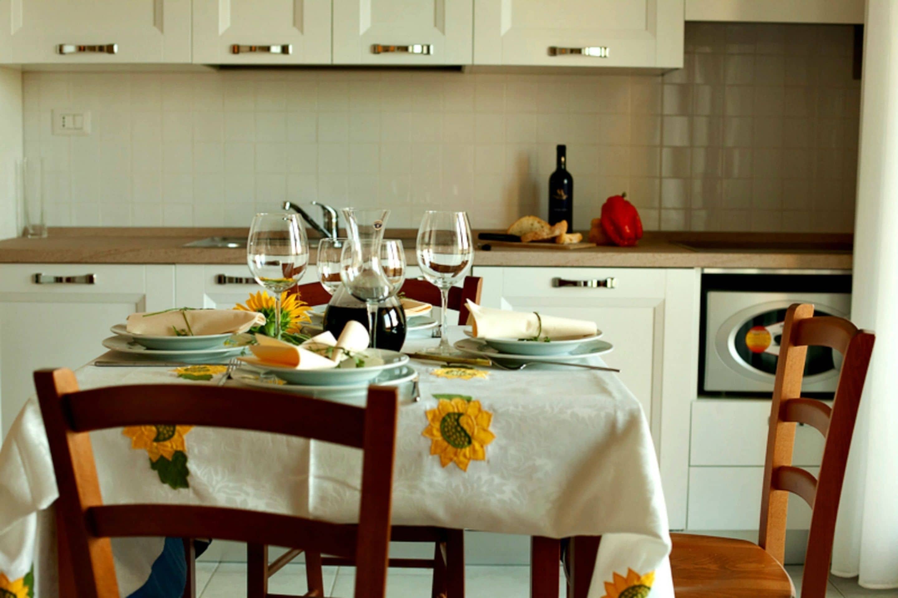 Une table à manger dressée avec des assiettes, des verres et une bouteille, entourée de chaises en bois.