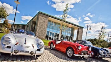 Classic cars on display in front of a sleek building with large windows.