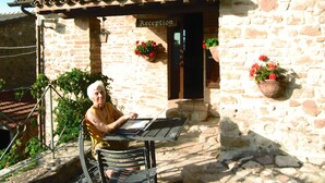 A stone building with a tiled roof, a reception sign, and flower pots on the exterior wall.