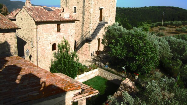 A stone building with a tower and a staircase leading to a window.
