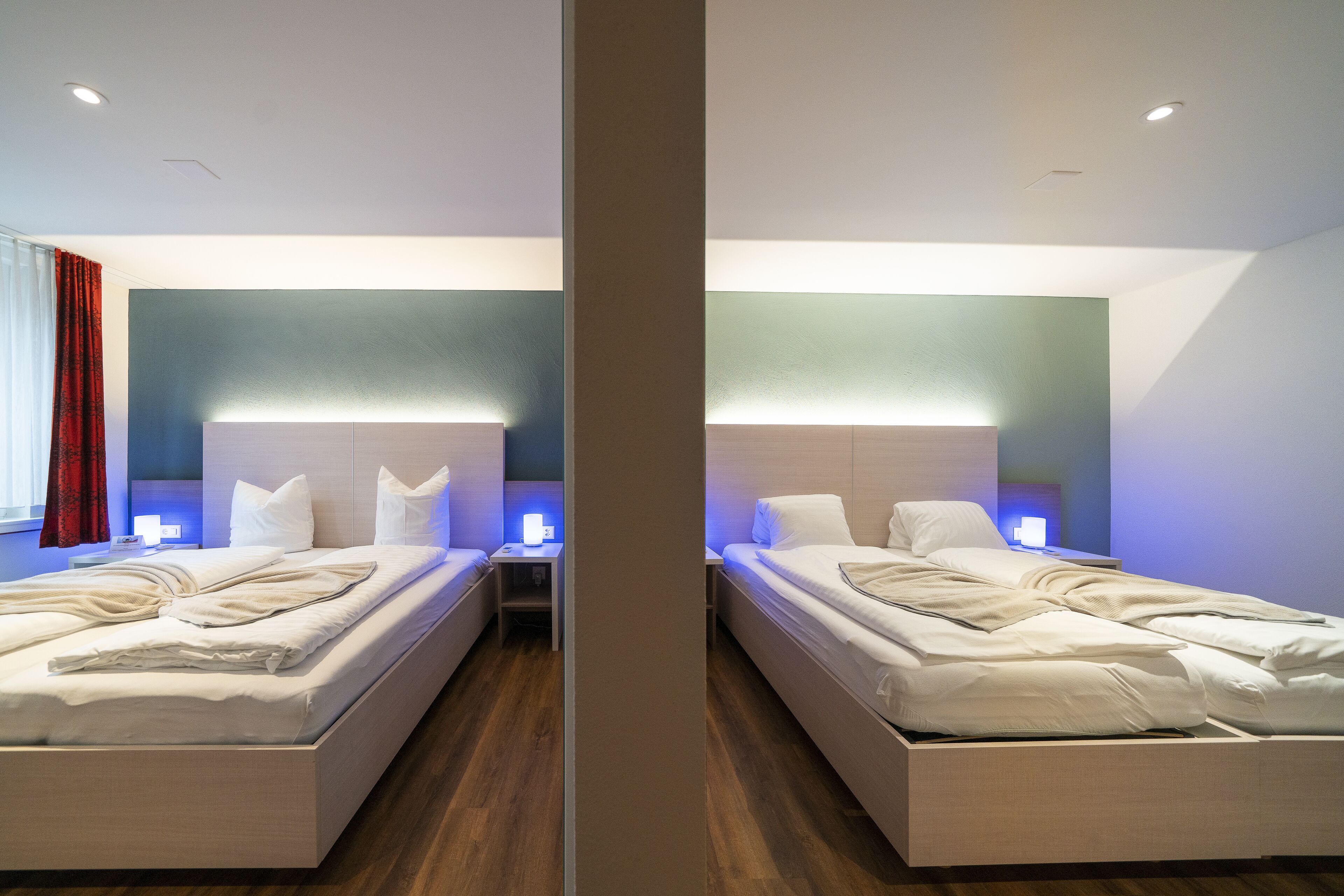A mirrored hotel room with two beds, bedside tables, and ambient lighting.