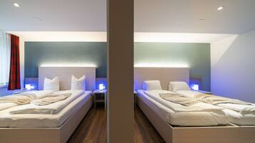 A mirrored hotel room with two beds, bedside tables, and ambient lighting.
