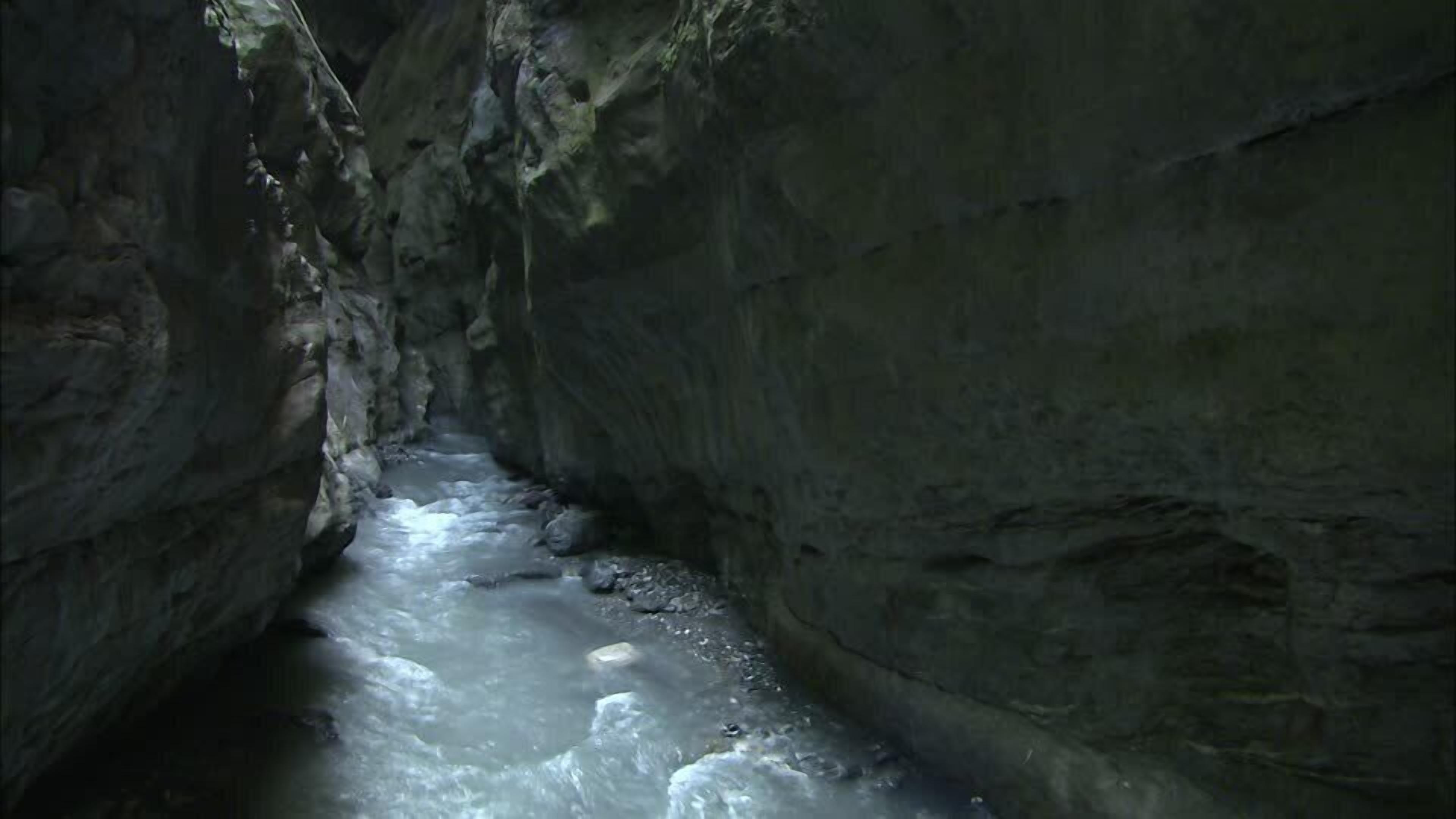 A narrow, rocky canyon with a flowing stream.