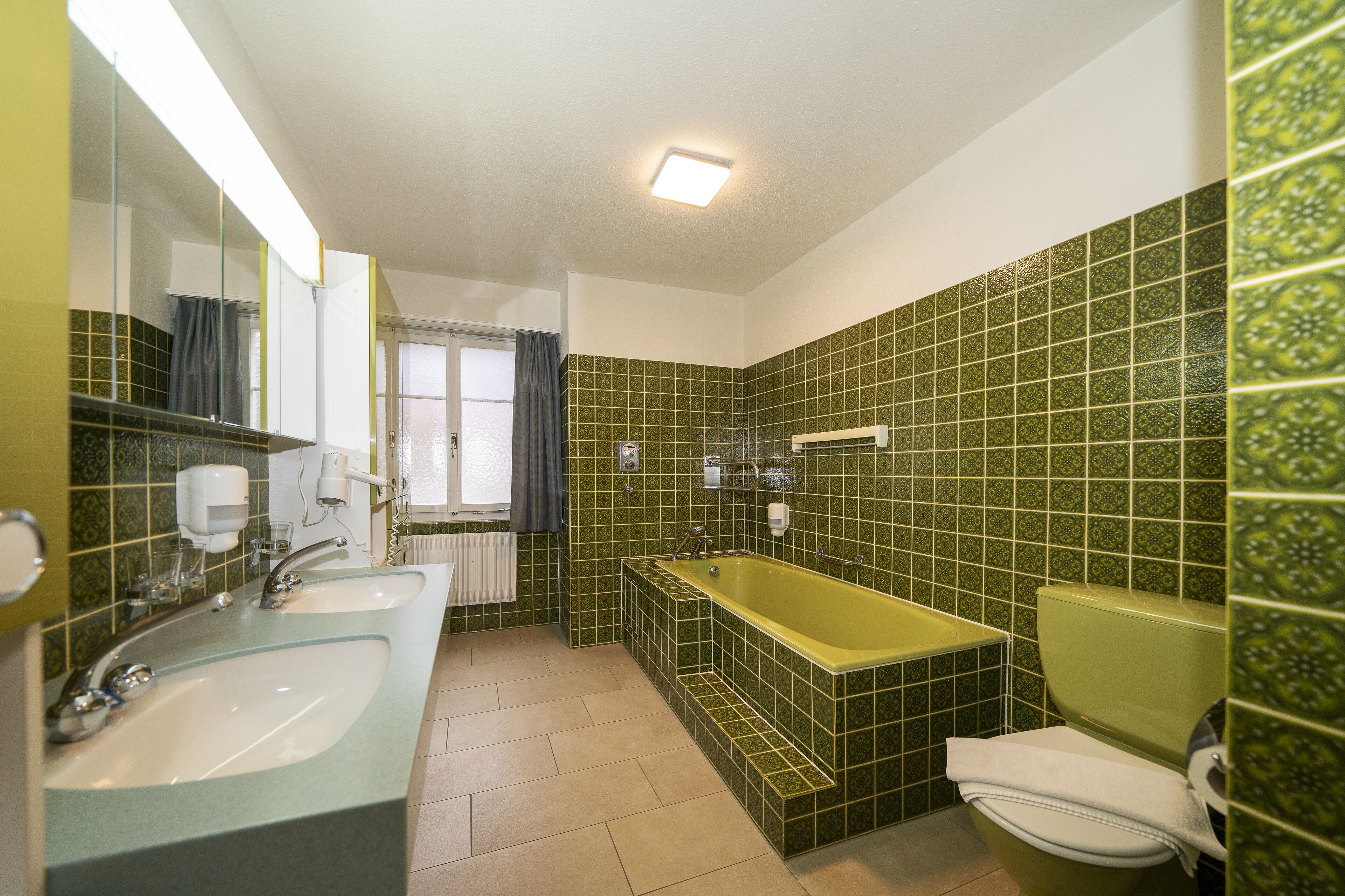 A bathroom with two sinks, a bathtub, and a toilet.