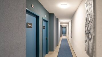 A hotel hallway with blue doors numbered 204 and 205, a blue carpet, and a wall with circular metal decorations.