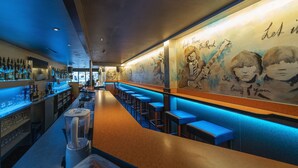 A bar area with a long counter, stools, and a wall with artwork. - Hotel Post (Sargans)