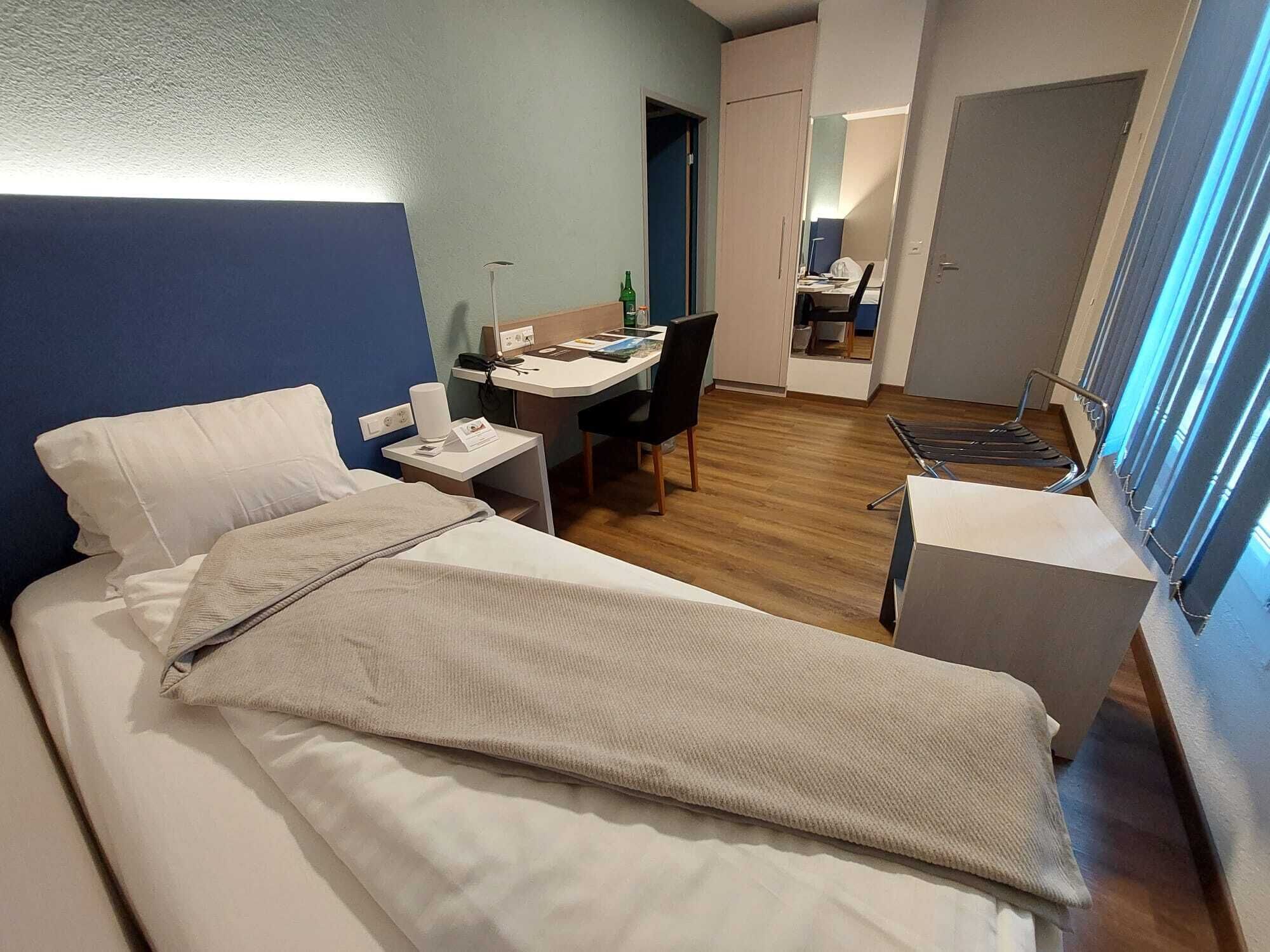 A hotel room with a bed, a desk, and a chair.