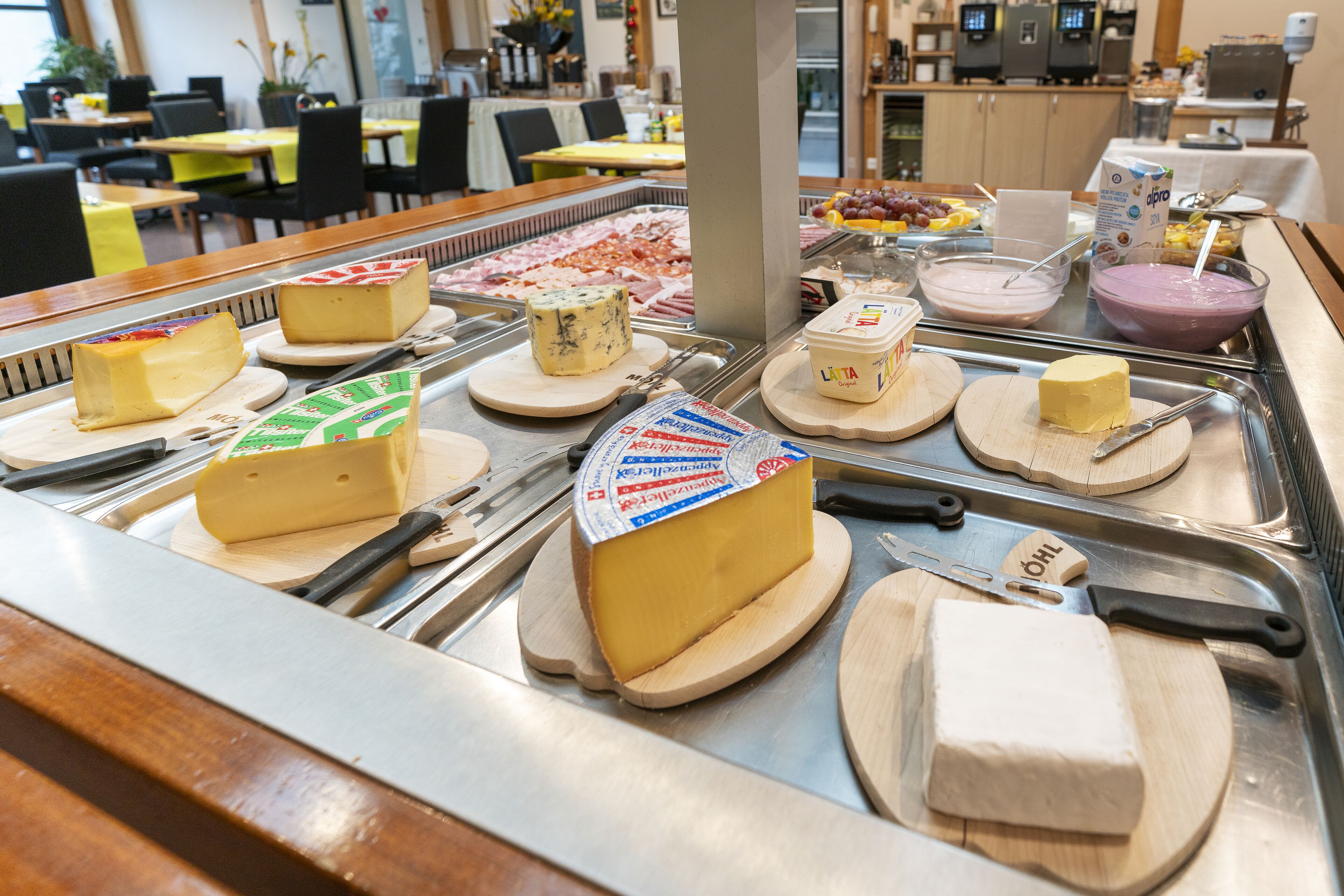 Un présentoir de fromages avec différents types de fromages et des ustensiles de découpe.