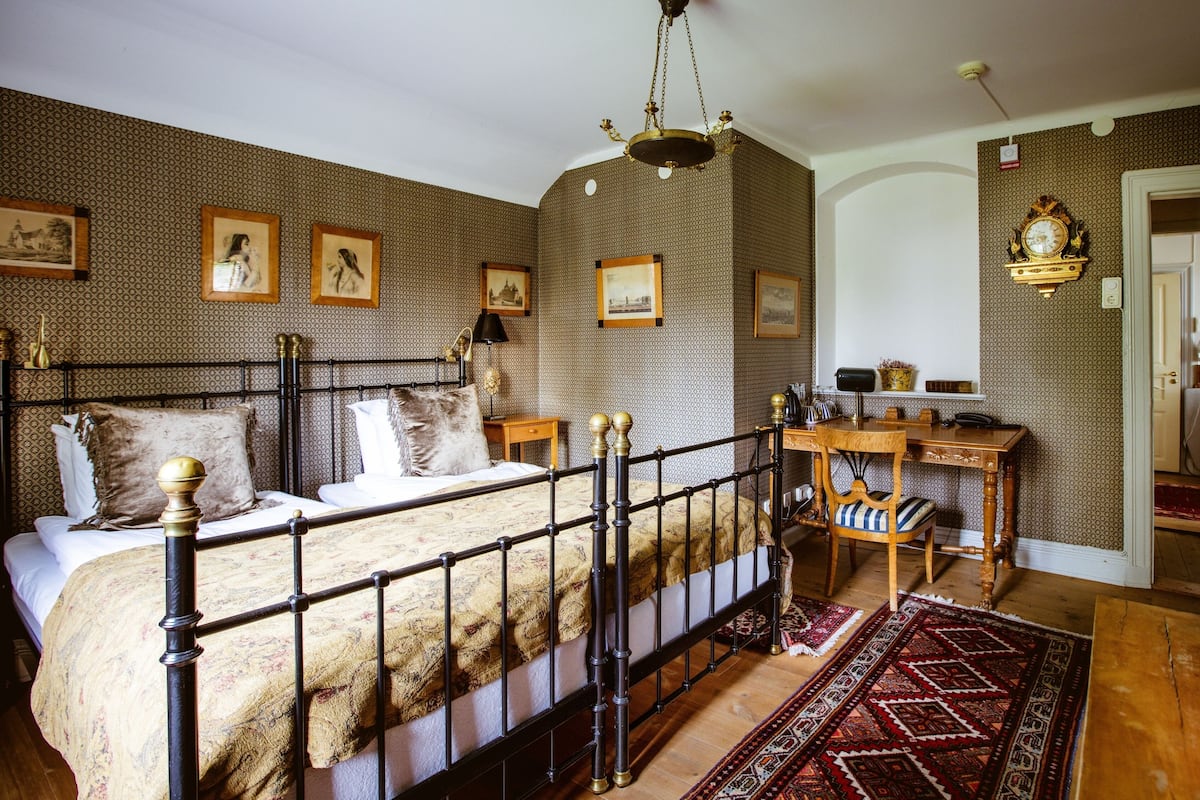 Ein Schlafzimmer mit Bett, Schreibtisch, Stuhl, Teppich und einer Chandelier.