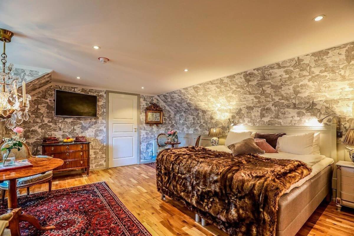 Ein Schlafzimmer mit einem großen Bett, einem Holzkleiderschrank, einem Fernseher und einer Kristallleuchter.