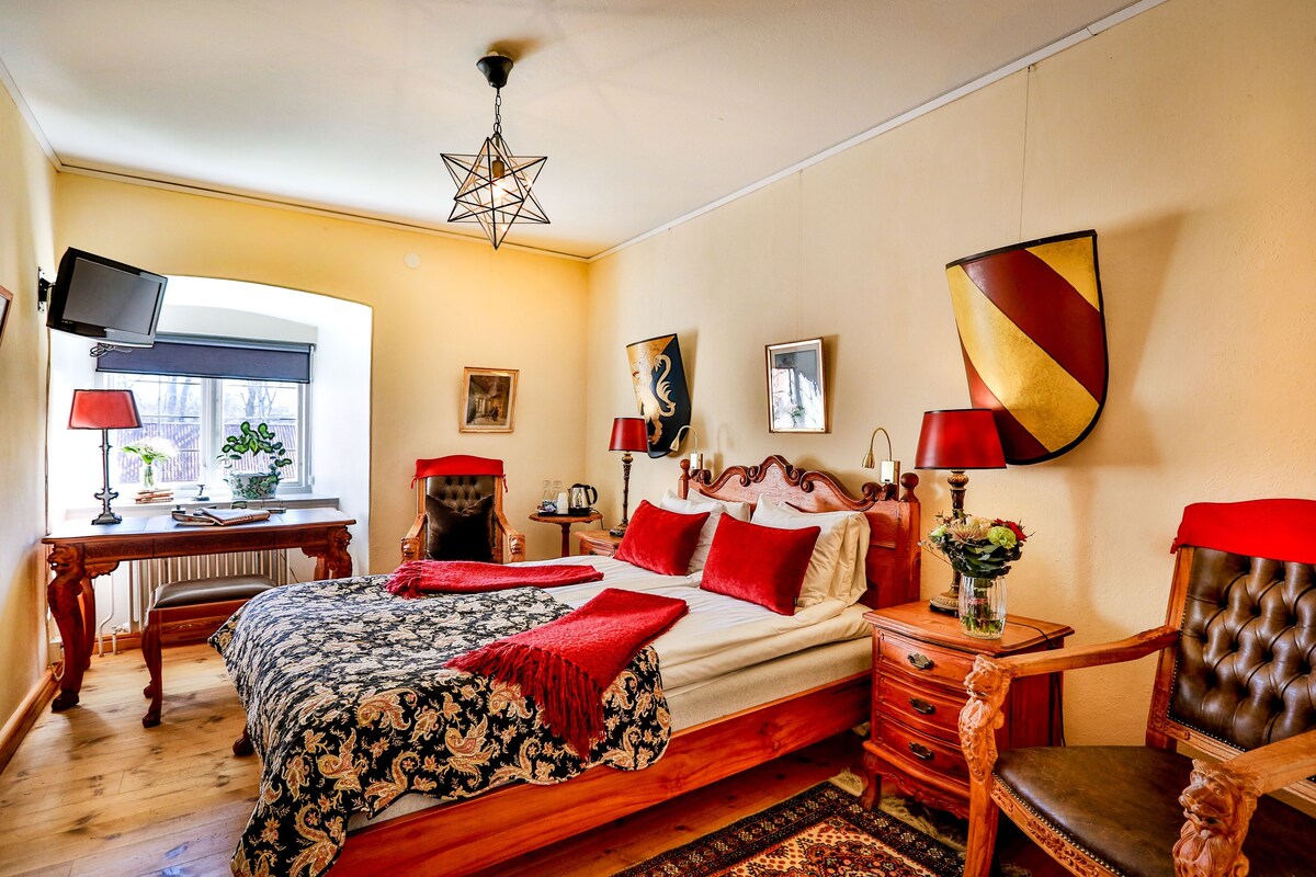 Een slaapkamer met een bed, een bureau, een stoel, een televisie en kunstwerken aan de muren.