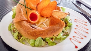 A plate with a salad, a fried item, and a decorative sauce. - Logis Hôtel Le Chene Dore (La Loupe)