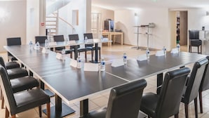 A conference room with a long table, multiple chairs, water bottles, and name cards. - Logis Hôtel Le Chene Dore (La Loupe)