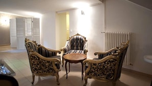 A room with ornate, gold-accented furniture, including two armchairs and a small table, with a radiator and a door in the background. - Logis Hôtel Le Chene Dore (La Loupe)
