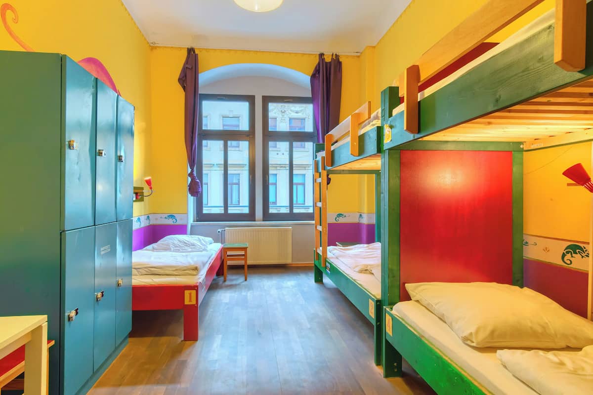A room with bunk beds, a radiator, and a window with curtains.