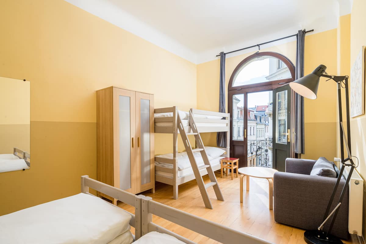 A room with bunk beds, a sofa, a desk, and a lamp.