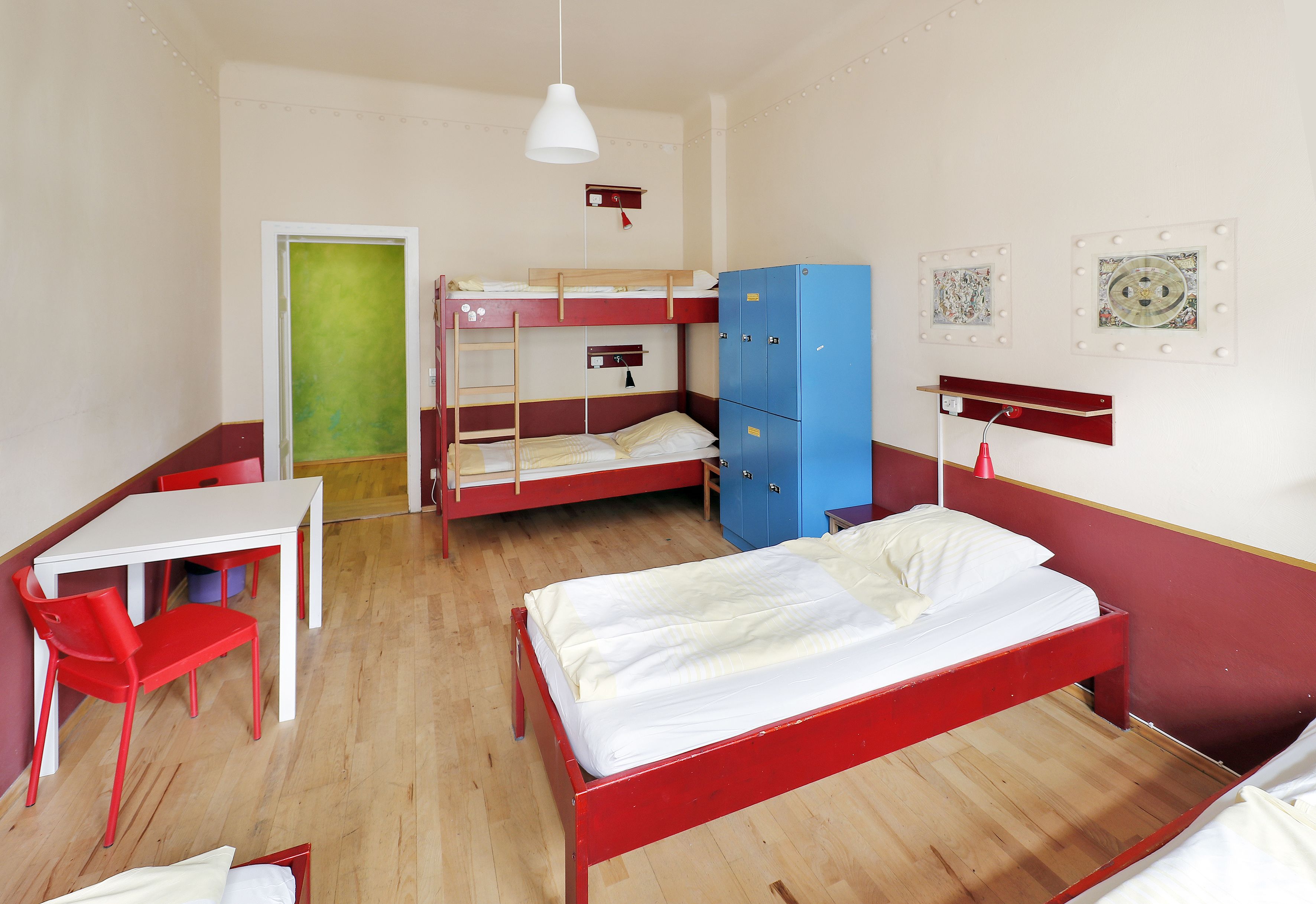 Ein Schlafsaalzimmer mit Etagenbetten, einem Schreibtisch, Stühlen und einem Kleiderschrank.