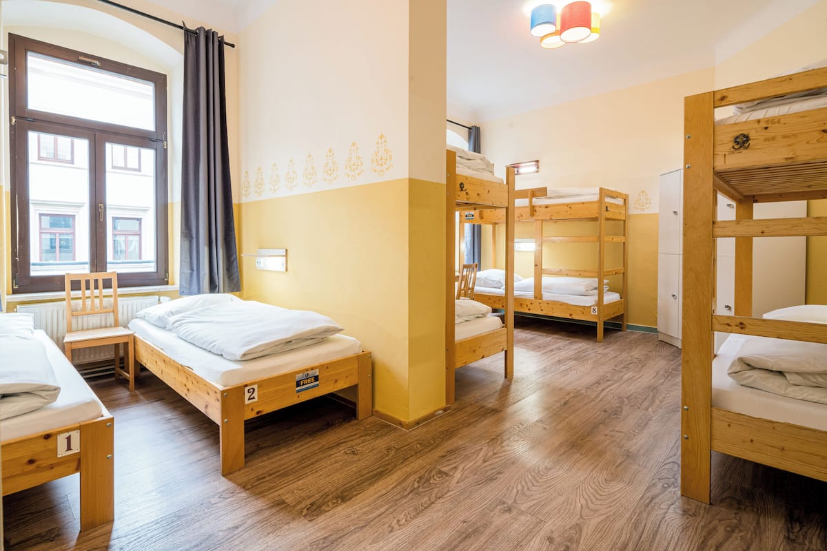 A dormitory room with bunk beds, a desk, and a chair.