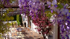 A patio area with a table and chairs, a pergola, and a flowering tree. - Le Nouvel (Portes-les-Valence)