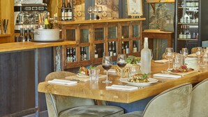 A restaurant with a long wooden table set for dining, wine glasses, bottles, and a variety of dishes. - Le Nouvel (Portes-les-Valence)