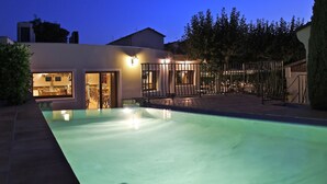 A swimming pool with a patio area, a covered outdoor seating area, and a building with multiple doors and windows. - Le Nouvel (Portes-les-Valence)