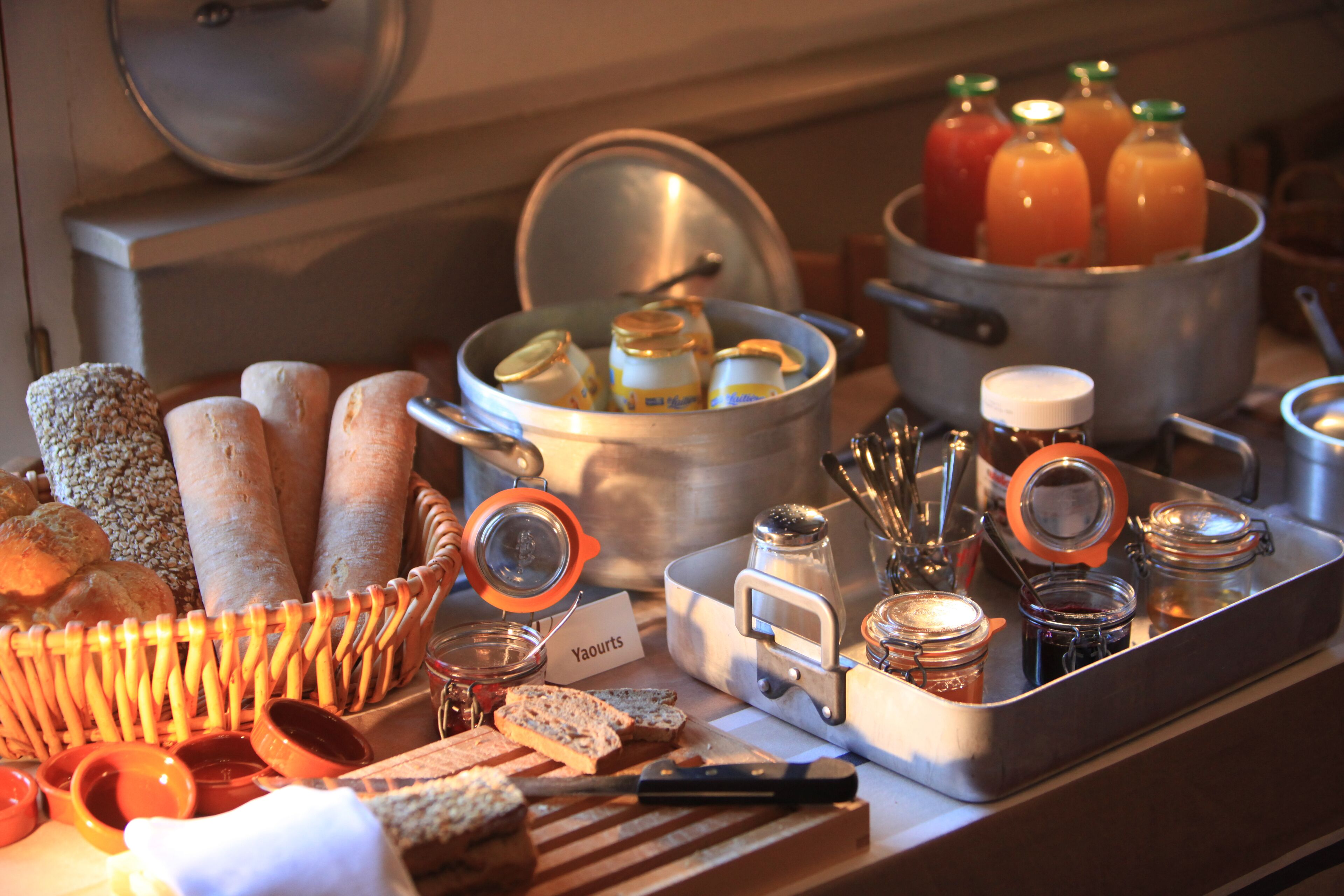 A breakfast buffet with various breads, jams, and juices.