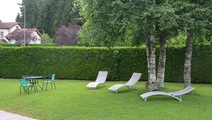 A well-maintained lawn with lounge chairs and a table, suggesting a relaxing outdoor area. - Hôtel Restaurant Au Perce Neige (Bonnetage)