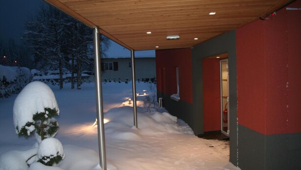 A snow-covered pathway leading to a building with a wooden ceiling and red and grey walls. - Hôtel Restaurant Au Perce Neige (Bonnetage)