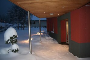 A snow-covered pathway leading to a building with a wooden ceiling and red and grey walls. - Hôtel Restaurant Au Perce Neige (Bonnetage)