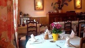 A dining area with a table set for two, a vase with flowers, and framed artwork on the walls. - Le Pont d'Or (Barjols)
