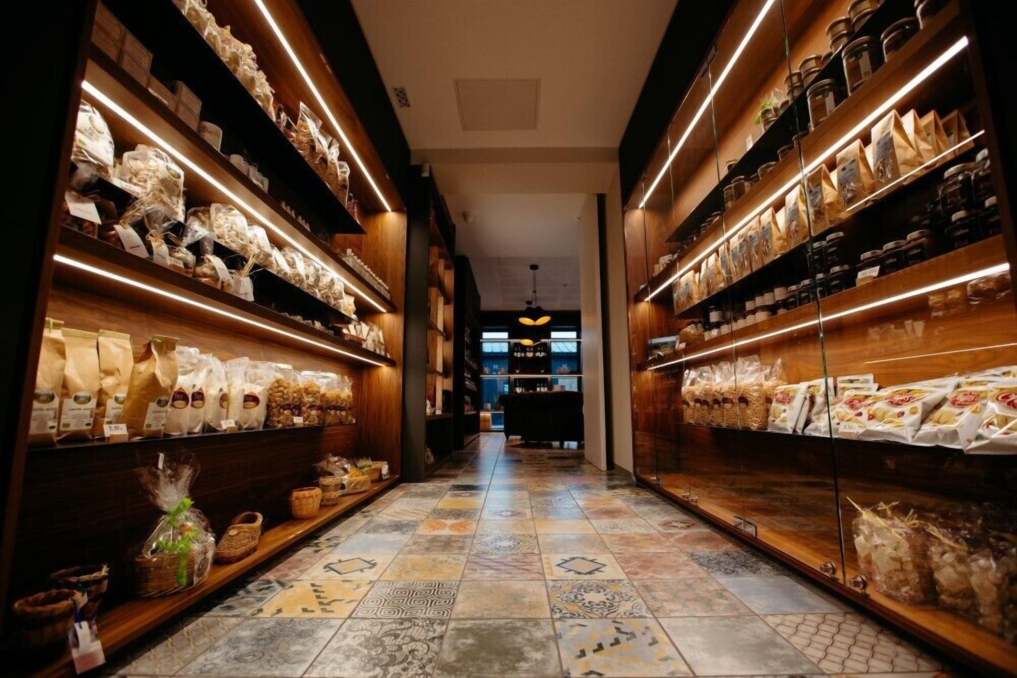 A corridor with shelves on both sides displaying various packaged goods and baskets.