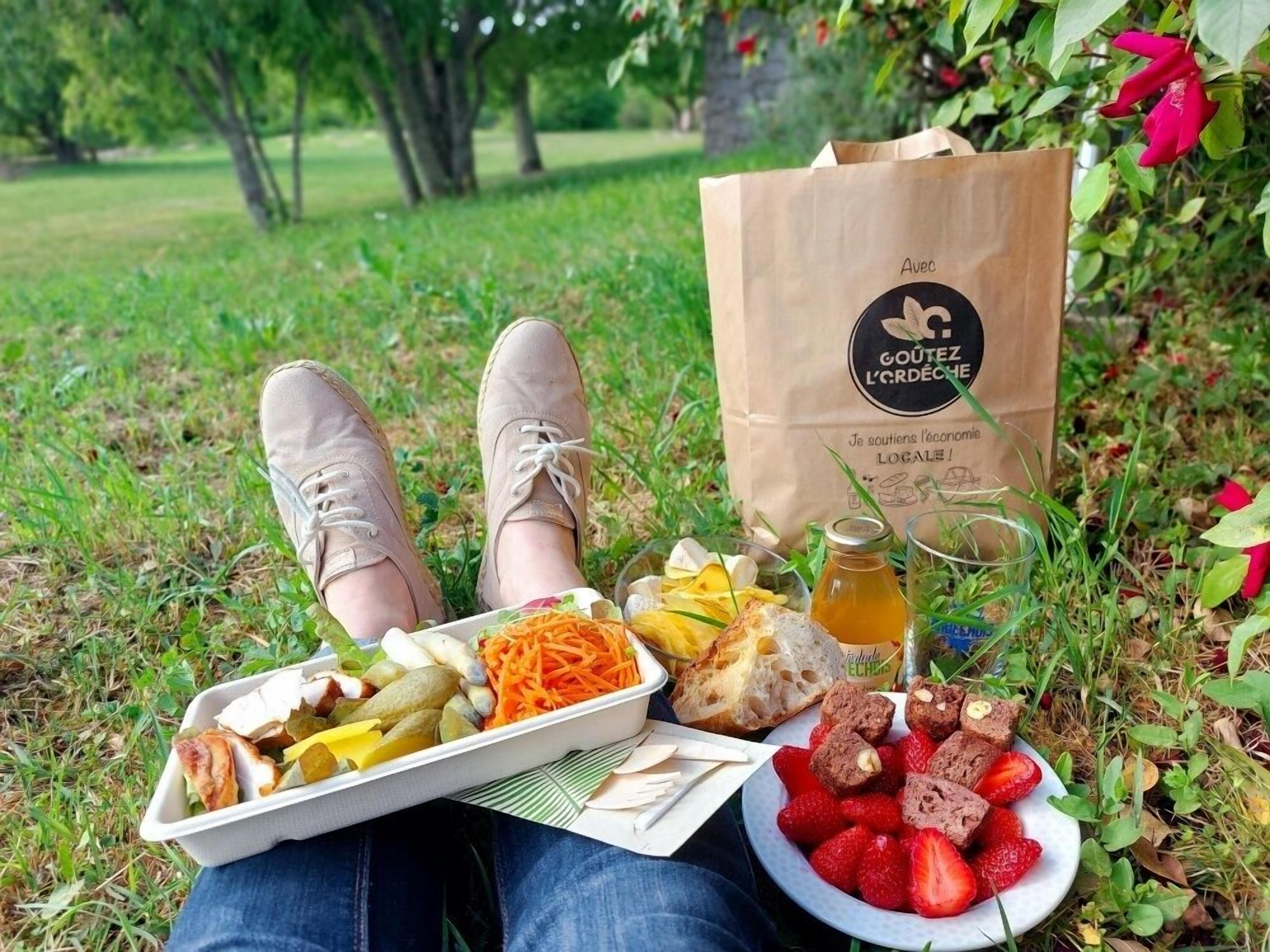 Ein Picknick mit Lebensmitteln, einer Tasche und einer Flasche auf der Wiese.