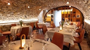 Un restaurante con paredes de piedra, mesas redondas y sillas color naranja.