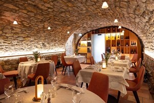 Um restaurante com paredes de pedra, mesas redondas e cadeiras laranja.