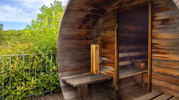 Una cabaña de madera con un banco y una mesita, rodeada de follaje.