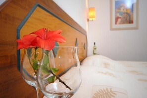 A clear glass vase with a red flower on a wooden headboard.