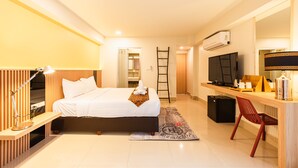 A hotel room with a bed, desk, TV, and a mirror. - The Golden Ville Boutique Hotel & Spa (Pattaya)