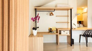 A modern, compact room with a wooden desk, a chair, a small shelf with a plant, and a mirror. - The Golden Ville Boutique Hotel & Spa (Pattaya)