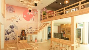 A traditional Japanese interior with wooden furniture, a staircase, and a mural of a wave and cranes. - The Golden Ville Boutique Hotel & Spa (Pattaya)