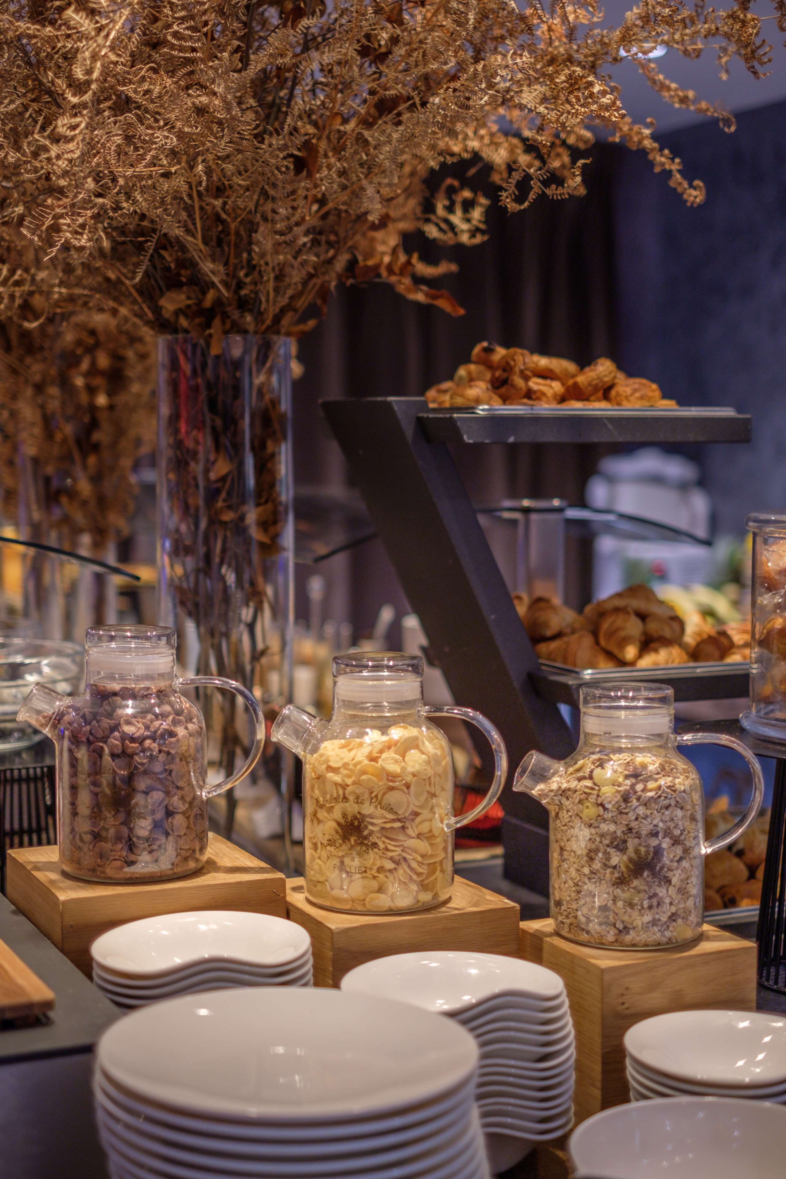 A buffet setup with various food items and beverages in glass containers, arranged on wooden stands.
