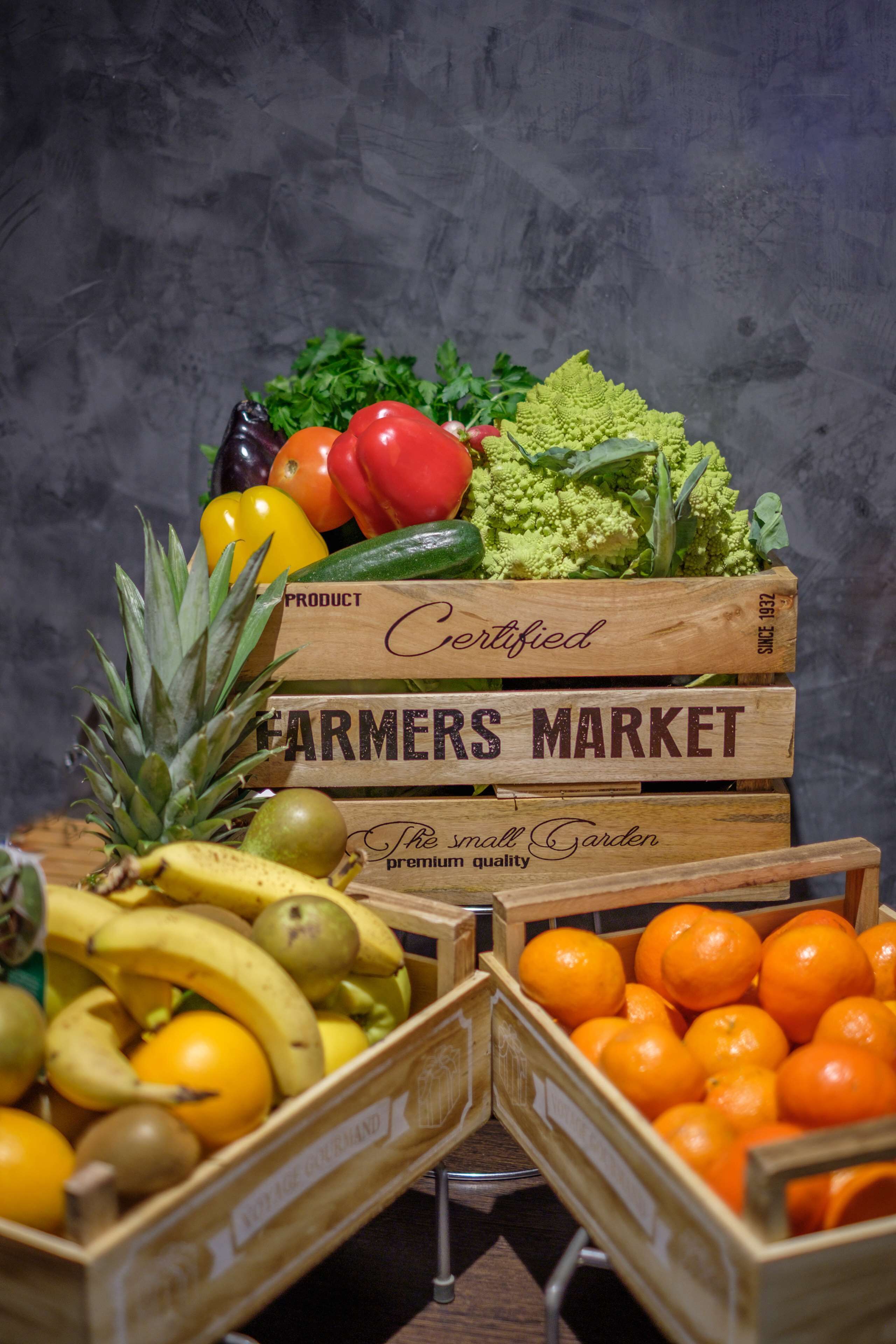 Vers fruit en groenten gepresenteerd in houten kisten, gelabeld met 'Farmers Market' en 'Gecertificeerd'.