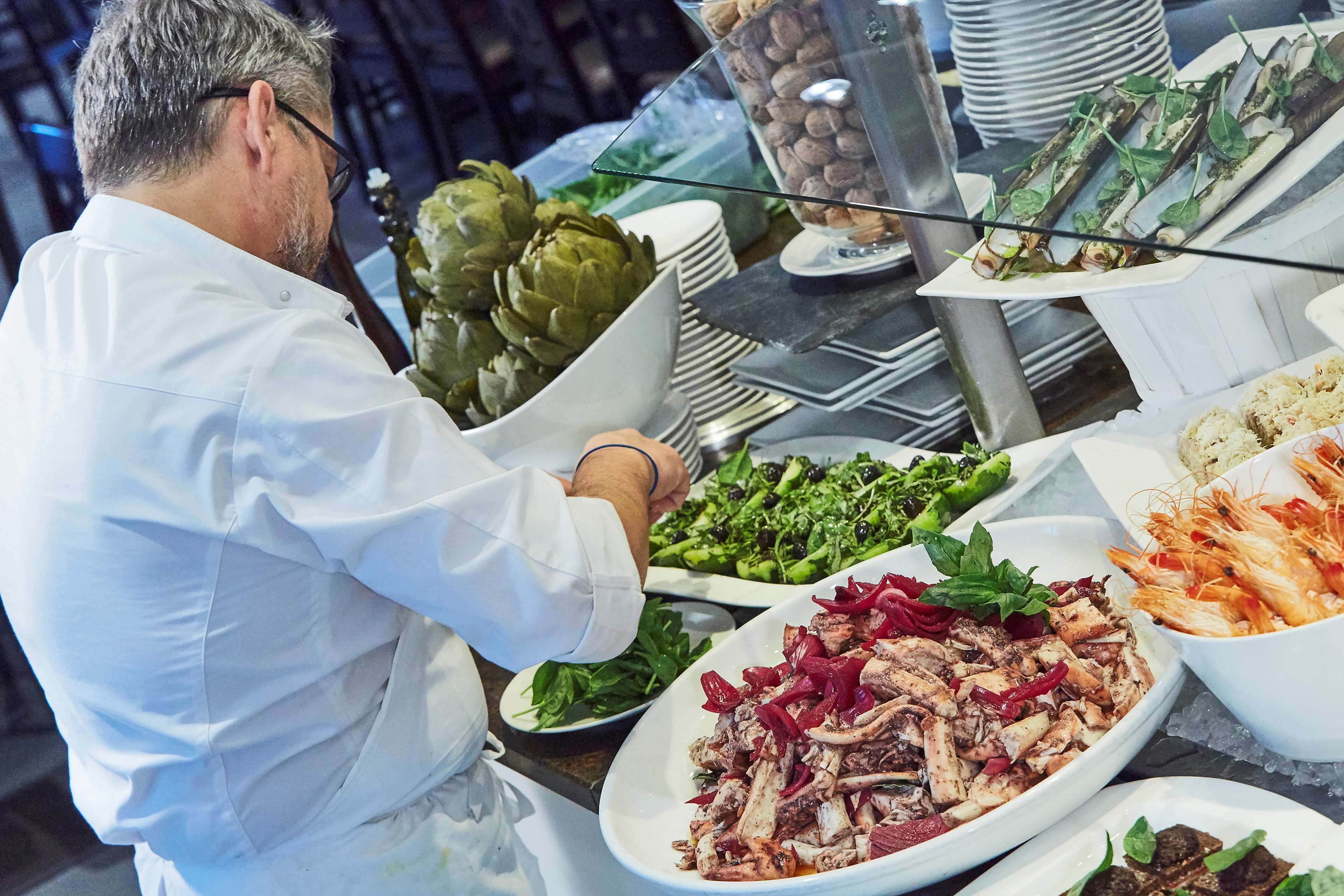 Un bufé con una variedad de platos, incluyendo mariscos, ensaladas y verduras.