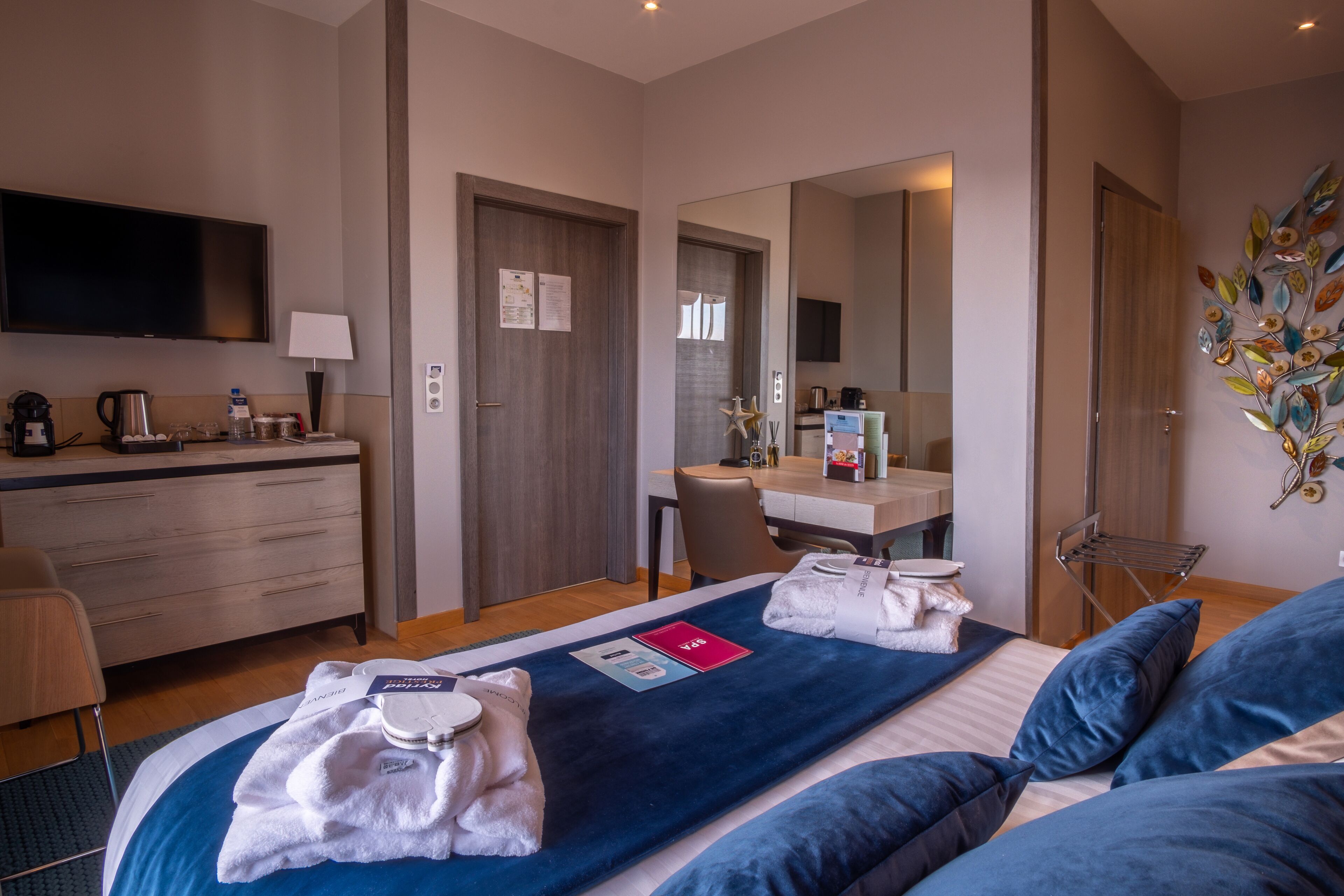Une chambre d’hôtel équipée d’un lit, d’un bureau, d’une chaise, d’une télévision et d’un miroir.