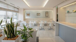 Una moderna zona de recepción con mobiliario blanco, plantas en macetas y obras de arte enmarcadas en las paredes.
